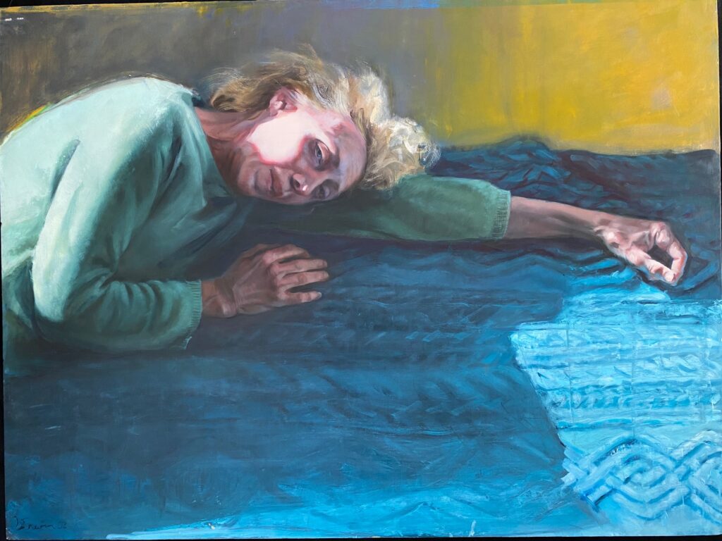 Image: Gaela Erwin, Shelly: California Dreaming, 2021, oil on canvas, 30" x 40". A painting depicting a woman in a green sweater laying across a blue blanket. She looks directly at the viewer. Photograph by Gaela Erwin. 