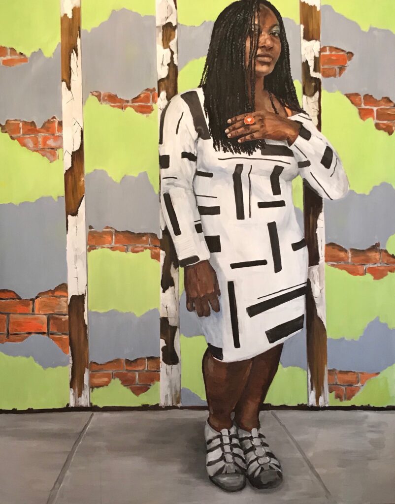 Image: Sandra Charles, Your Walls, An Artist and Venice (2019), oil on canvas, 2018,  48 x 60". A painting of a Black woman wearing a black and white dress standing in front of a green and grey brick wall. She looks directly at the viewer with one hand raised to her hair. Image courtesy of the artist.