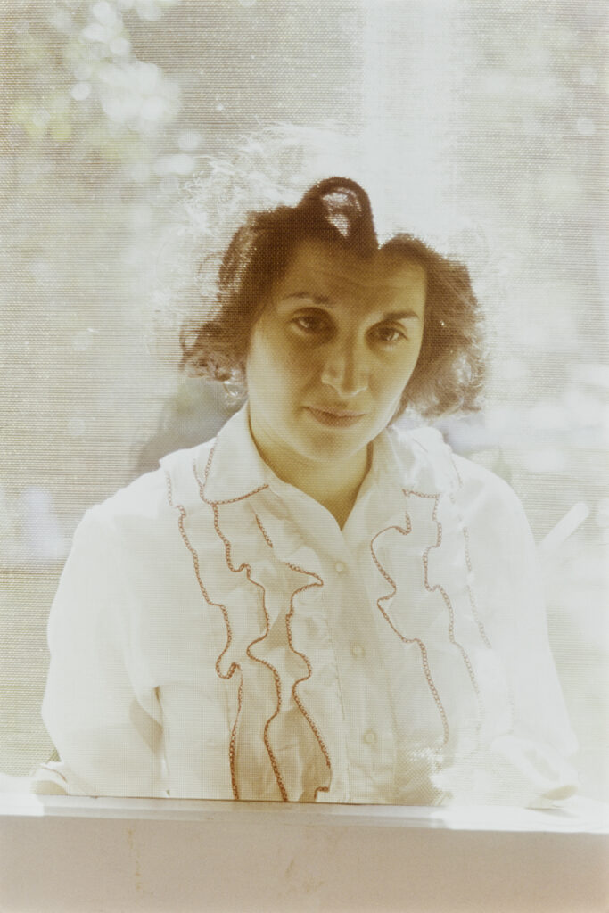 Image: Vivian Maier, Woman in a ruffled blouse. Location unknown, August 1960. Chicago History Museum, ICHi-189561 / © The Estate of Vivian Maier. A photograph of a white woman with brown hair wearing a white, ruffled blouse. She looks slightly down and to the viewer's right.