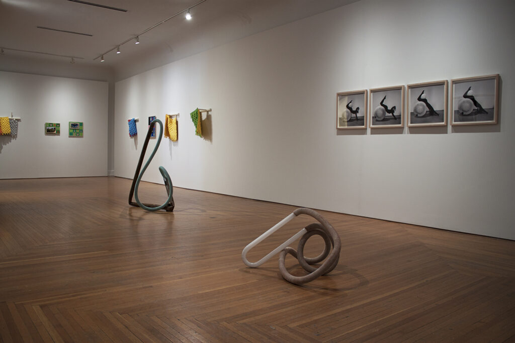 Image: An installation view of A Thought is a River, curated by John Knuth. Works by Matt Coors and Kiah Celeste are on display in The Carnegie’s Duveneck Gallery (Left to Right). Four black and white photos are on display together on the right, with more colorful pieces hanging to the left. Two organic-shaped sculpture sit on the gallery floor. Photo by CM Turner.