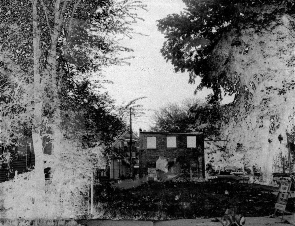 Image: A black and white photograph by Carlos Javier Ortiz. Englewood, Chicago, 2013. Ortiz: "An abandoned and boarded-up houses in Englewood. In time, nature tends to reclaim the landscape." Image courtesy of the artist.