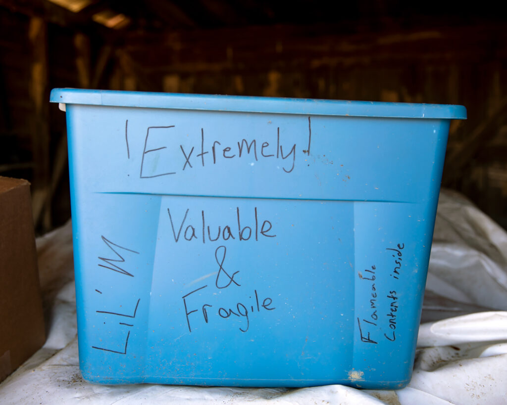 Image: A color photograph of a blue plastic storage tub with the words, "Extremely valuable and fragile" written on it with black marker. © Rachael Banks. Images courtesy of the artist.