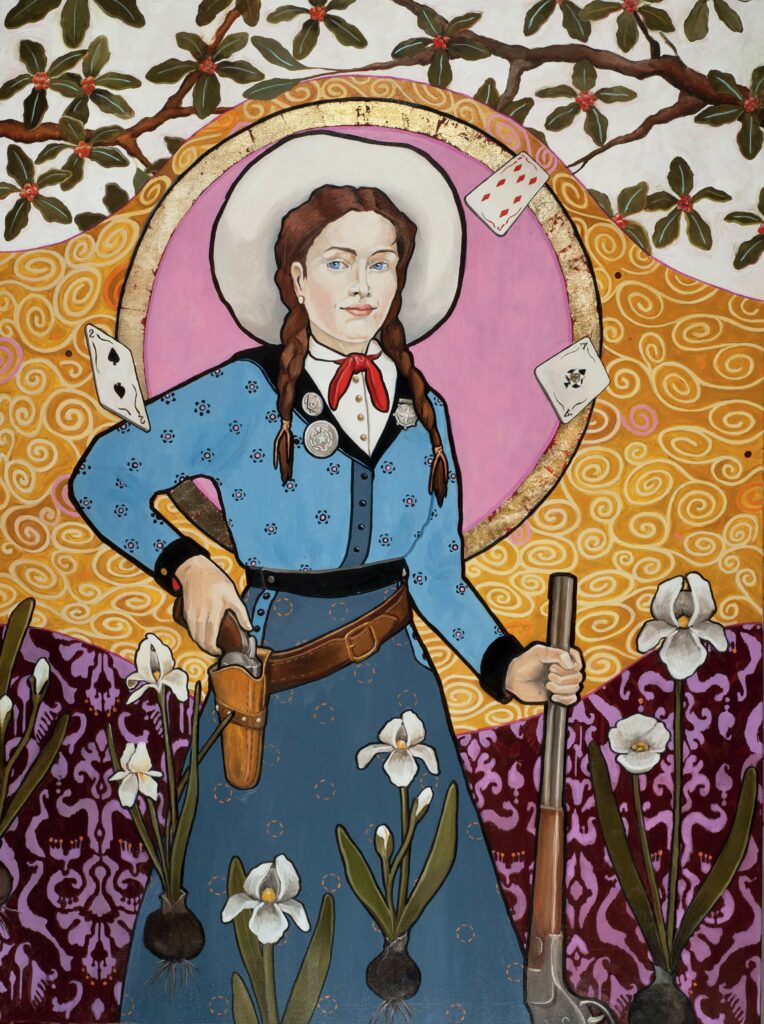 Image: Honora Jacob, Annie & The Ace of Spades, 2021, oil and gold leaf on canvas, 48” x 36”. A painting depicting Annie Oakley standing while holding a gun on her left side. Her right hand rests on a gun she is wearing in a holster. Playing cards float around her. The background shows various floral patterns and a gold halo-like circle is behind Annie's head. Image courtesy of the artist. 