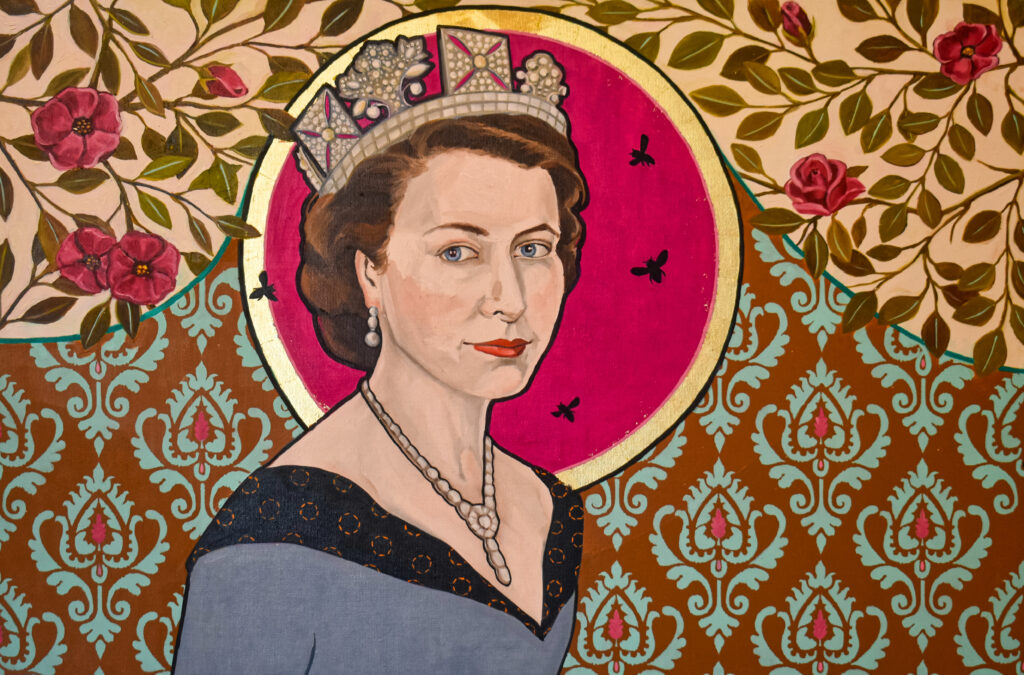 Image: Honora Jacob, HRH The Queen Bee, 2022, oil and gold leaf on canvas, 24” x 36”. A painting depicting Queen Elizabeth II. She looks directly at the viewer and wears a crown and fine jewelry. The background shows various floral patterns and a gold halo-like circle is behind the queen's head. Image courtesy of the artist.