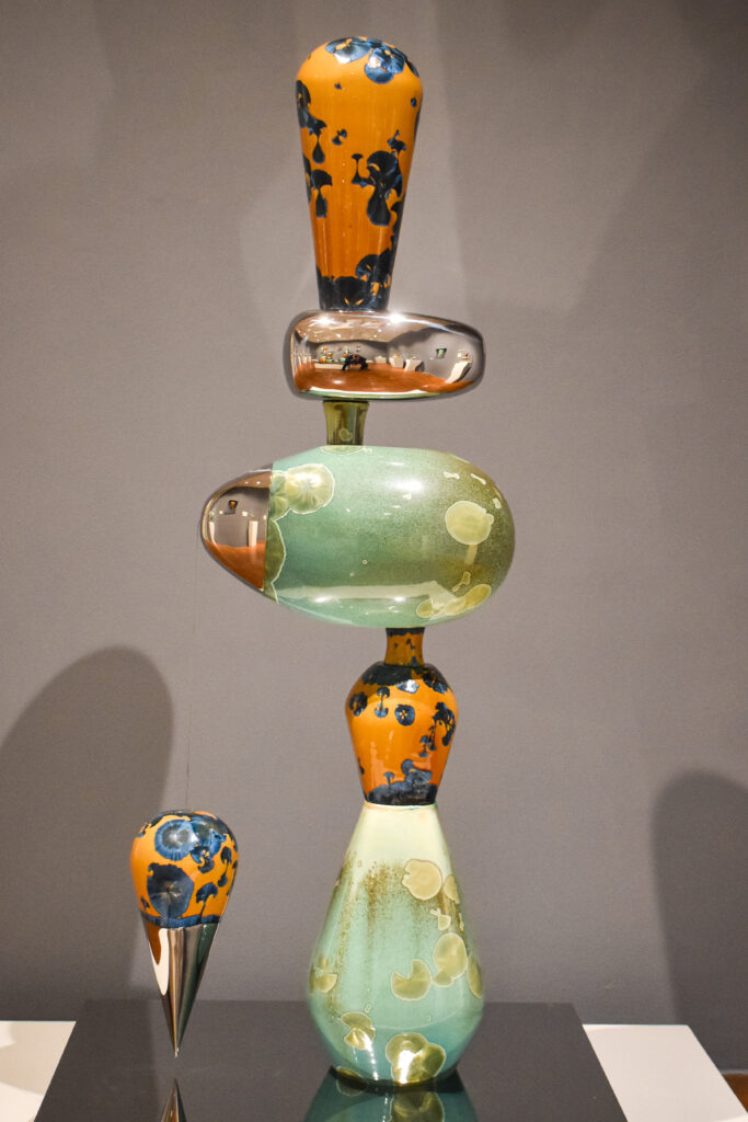Image: Li Hongwei, Allegory of Balance #18, porcelain and stainless steel, 61.5" x 27.5" x 21" x 5”. An silver, blue, orange, and mint-green sculpture that resembles organic shapes stacked on top of one another. Photo by Kevin Nance.