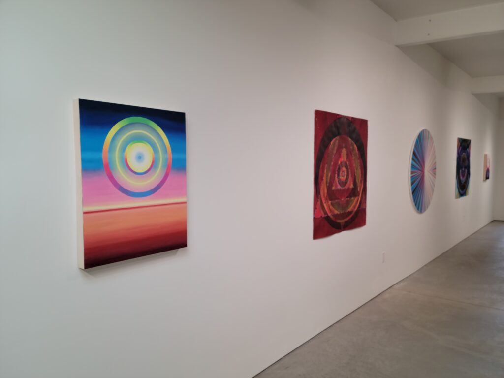 Image: Installation view of "Not a Certainty But a Circumstance" at Quappi Projects in Louisville, KY. Several brightly colored abstract pieces hang on the wall in the gallery. Photo by the author.