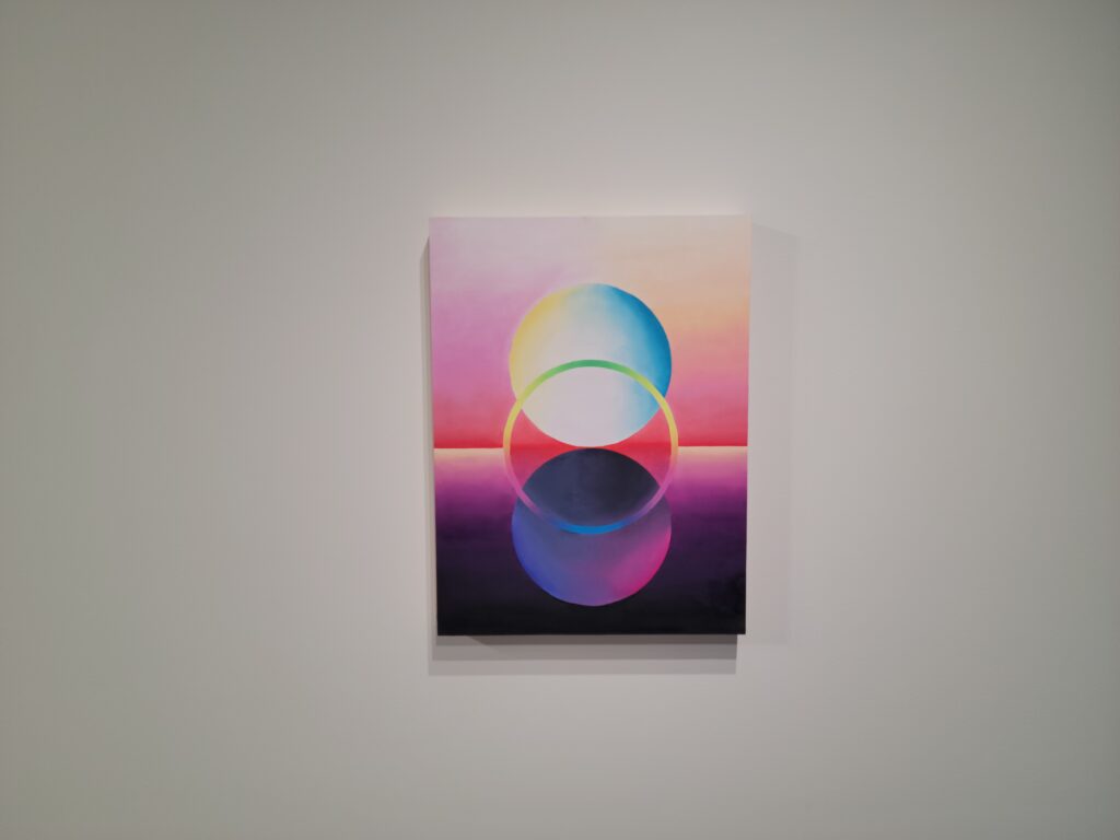 Image: Martin Benson, That Small Space Between My Hope and Fear, 2021, oil on canvas mounted to wood. A painting showing three overlapping circles in reds, pinks, blues, yellows, and blacks. Photo by the author