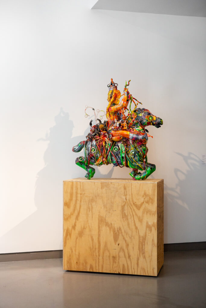Image: Robert Morgan, Queen Christina, 2010, mixed media. A colorful, assemblage-like sculpture that resembles a person on a horse sits atop a wooden pedestal. Image courtesy of 21c Lexington.