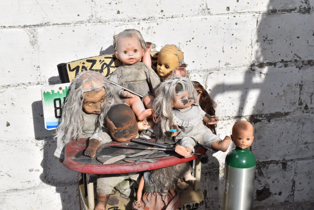 Image: Eight dolls arranged in a basement installation at the Heidelberg Project. Photo courtesy of the author.