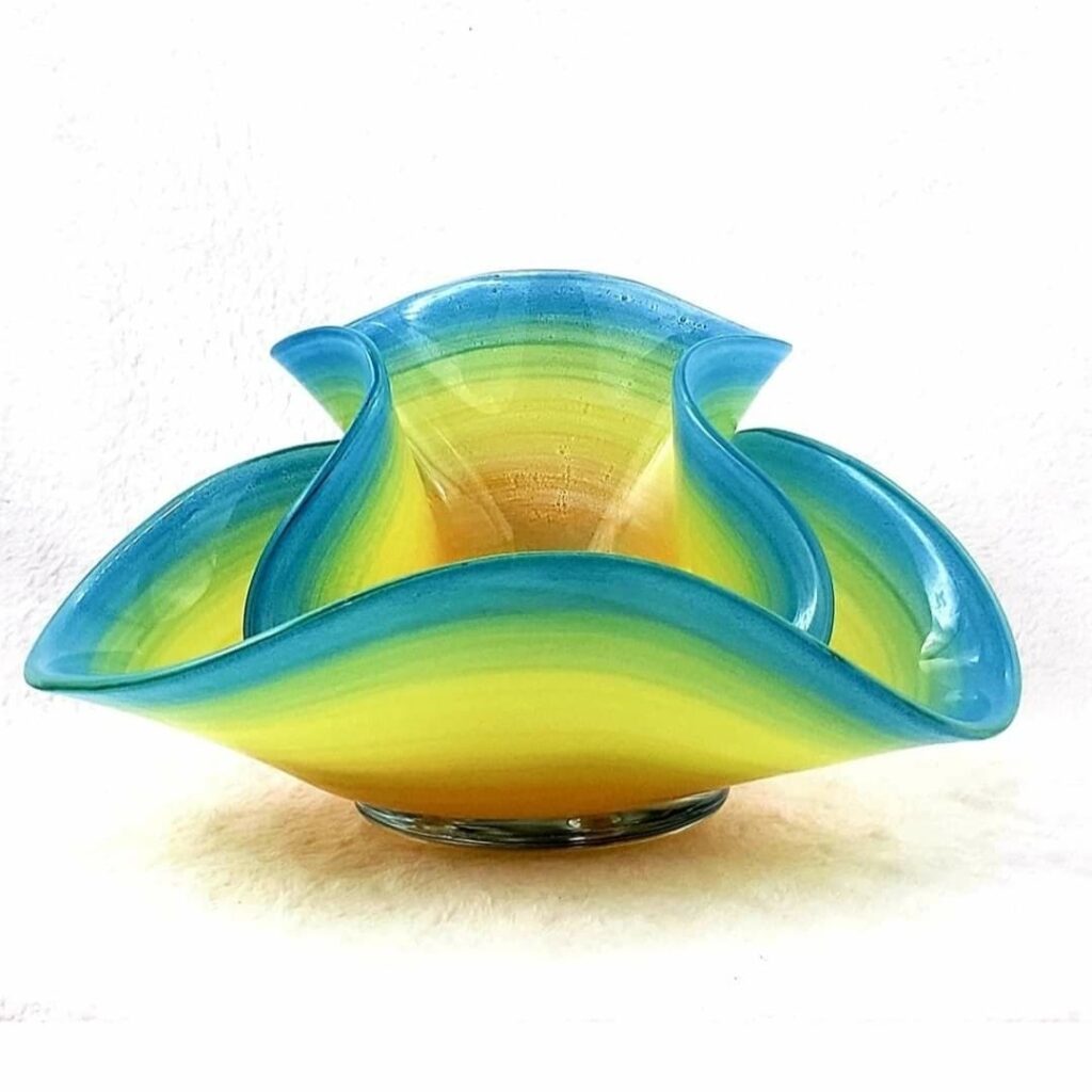 Image: Rialto by Mark Lenn Johnson. This piece is part of Johnson’s Tramonto Siblings series, which couples multiple shapes in a way that suggests a family unit. The piece is an organic-shaped glass piece made up of oranges, yellows, greens, and blues.Photo courtesy of the artist.
