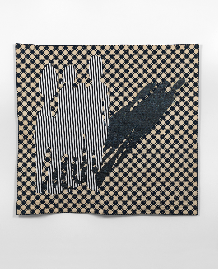 Image: Sanford Biggers, The Talk, 2016. Antique quilt, assorted textiles, tar, glitter. 80 x 84 in., ssbquilt060. © Sanford Biggers and Massimo De Carlo, photograph by Todd White Art Photography. A photo of a textile piece hanging on a white wall. The piece is mostly black and white and shows a group of figures with an elongated shadow.