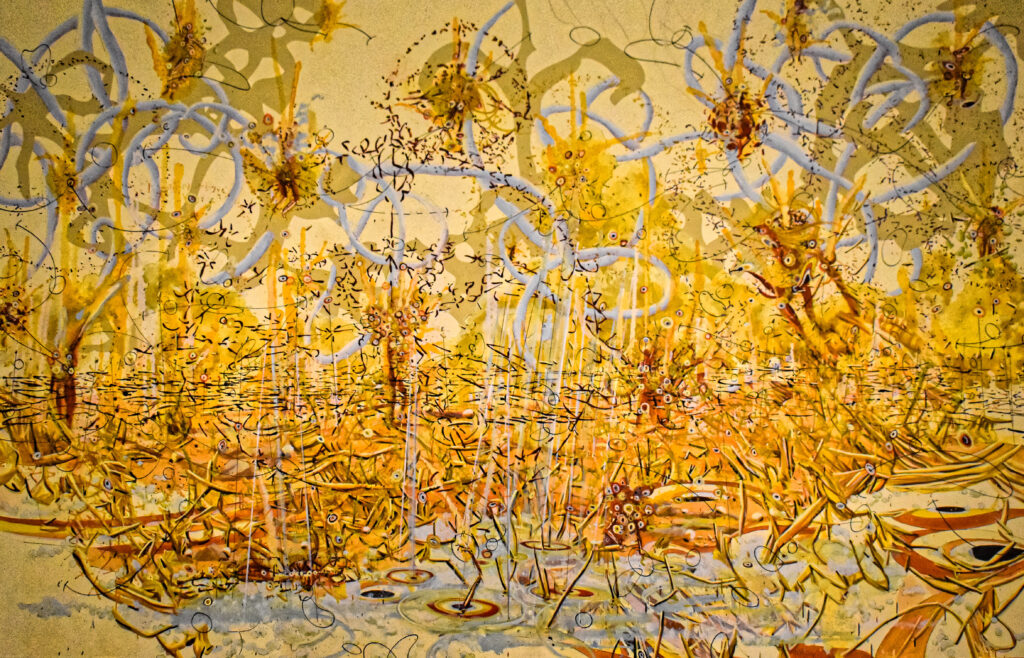 Image: A detail view of "No sign of the World" (2004) by Matthew Ritchie. The painting is mostly shades of yellow with some grey gestural marks. The painting is abstract. Photo by Kevin Nance.
